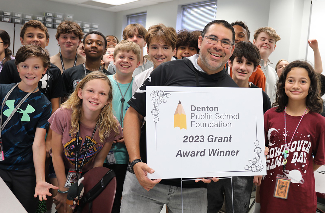 Staff holding sign with students